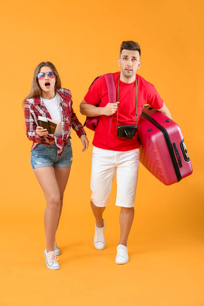 Worried couple of tourists with luggage on color background - Photo, Image