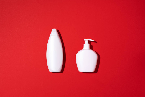 Shampoo and soap bottles on red background. Top view. Flat lay. Copy space. - Foto, immagini