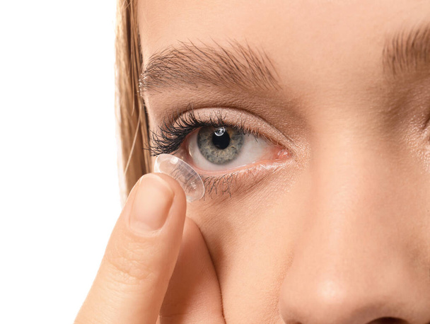 Young woman putting in contact lens on white background, closeup - Φωτογραφία, εικόνα