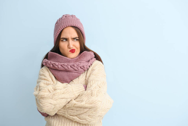 Displeased young woman in winter clothes on color background - Foto, afbeelding