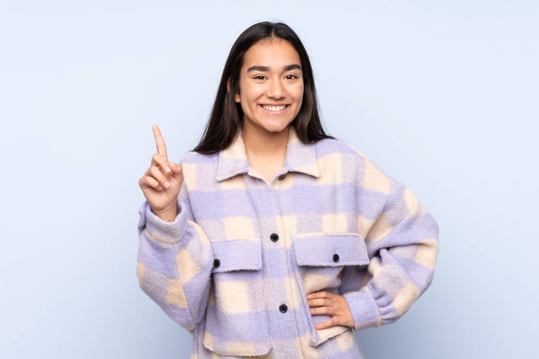 Young Indian woman isolated on blue background showing and lifting a finger in sign of the best - Photo, Image