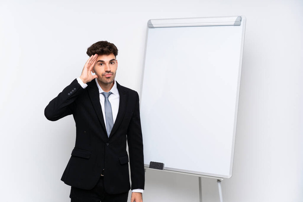 Νεαρός επιχειρηματίας δίνει μια παρουσίαση σε λευκό πίνακα με έκπληξη και σοκαρισμένη έκφραση προσώπου - Φωτογραφία, εικόνα