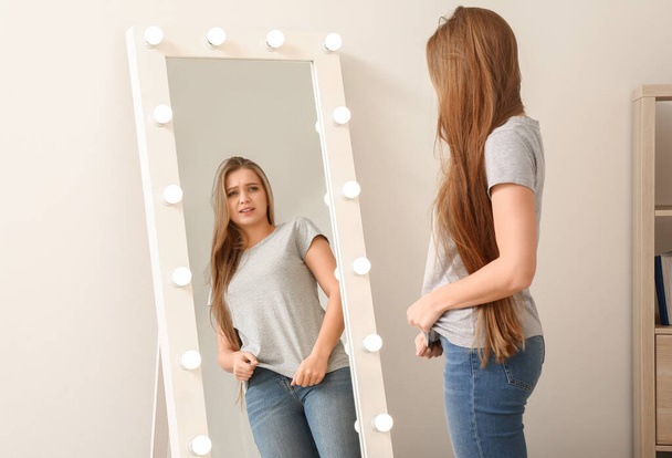 Giovane donna scontenta vicino specchio a casa
 - Foto, immagini
