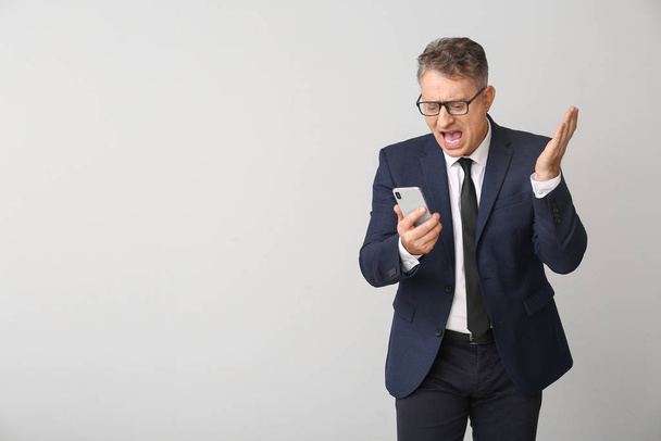 Stressed businessman with mobile phone on white background - Photo, Image