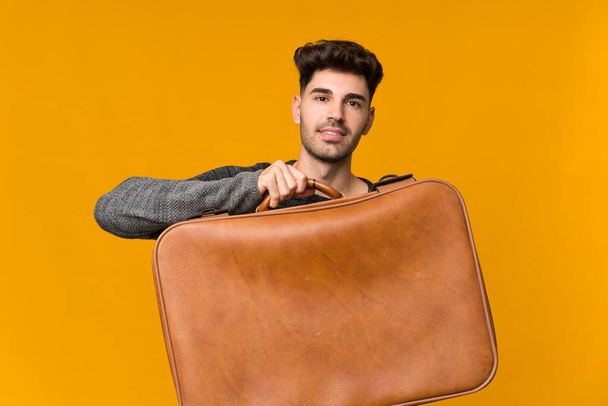 Mladý muž nad izolovaným pozadím drží starožitný kufřík - Fotografie, Obrázek