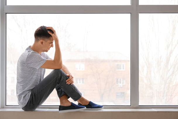 Depressieve jongeman bij het raam - Foto, afbeelding