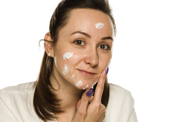 Egy nő alkalmazó arckrém fehér háttér - Fotó, kép