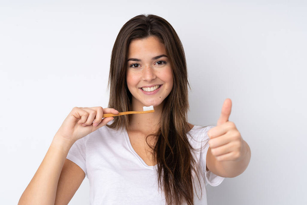 Teenager dívka přes izolované pozadí s kartáčkem na zuby - Fotografie, Obrázek