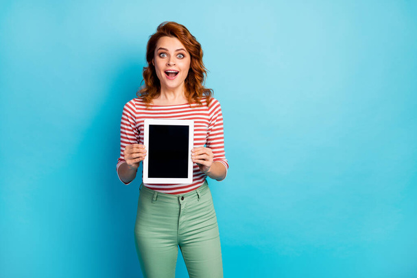Portrait of astonished funky woman hold new tablet she display new modern technology novelty scream wow omg wear stylish pullover isolated over blue color background - Foto, Imagem