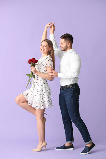 Heureux jeune couple avec bouquet de fleurs sur fond de couleur
 - Photo, image