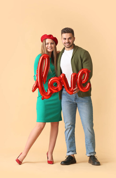 Boldog fiatal pár léggömb alakú szó Szerelem a színes háttér - Fotó, kép