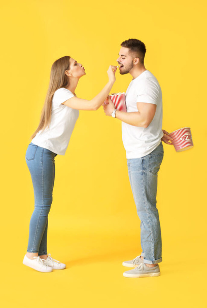 Emotional young couple with popcorn on color background - Fotografie, Obrázek