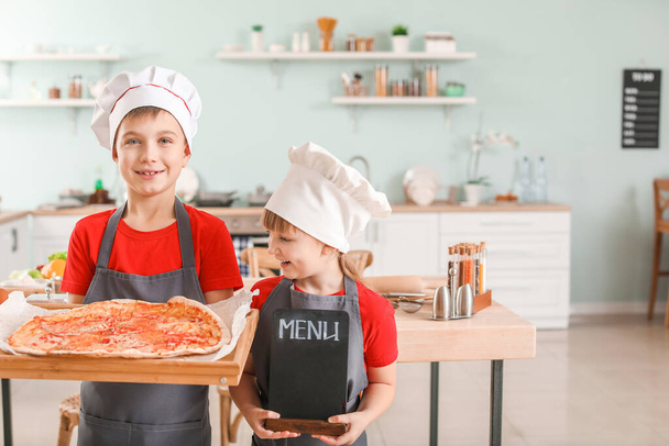 Petits chefs mignons avec pizza et menu dans la cuisine
 - Photo, image