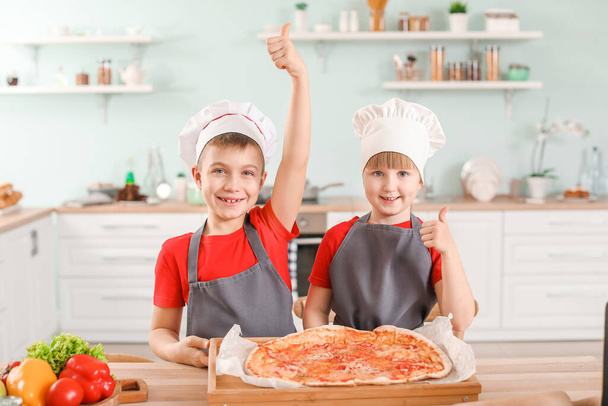 Cute little chefs with pizza in kitchen - Фото, изображение