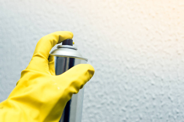 painting the walls of the spray. hand in yellow rubber gloves holding spray paint. repairs - Valokuva, kuva