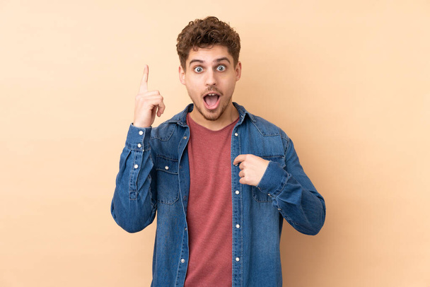 Caucasian man isolated on beige background with surprise facial expression - Fotó, kép