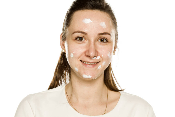 mujer feliz posando con crema facial sobre fondo blanco
 - Foto, imagen