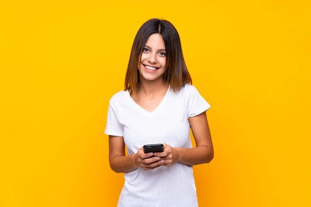 Nuori nainen yli eristetty keltainen tausta lähettää viestin mobiili - Valokuva, kuva