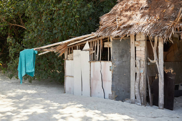 Een hut gebouwd van planken en riet op een zandstrand op een zonnige dag - Foto, afbeelding