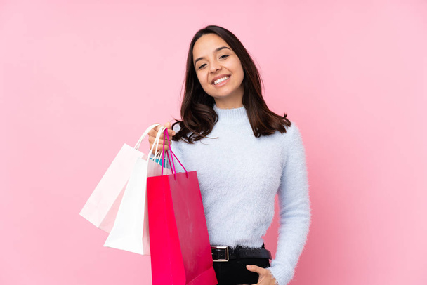 fiatal nő bevásárló táska felett elszigetelt rózsaszín háttér nevetés - Fotó, kép