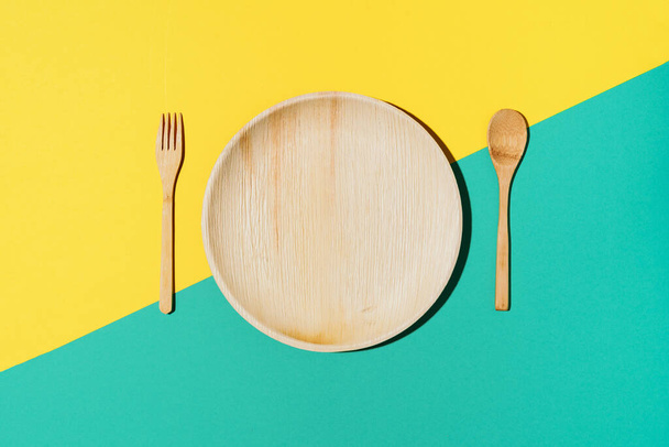 Disposable tableware from natural materials, wooden spoon, fork on yellow background. Eco-friendly sustainable lifestyle. Concept of bamboo, wooden or paper disposable tableware - Foto, Imagem