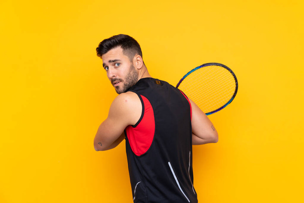 Férfi felett elszigetelt sárga háttér játszik tenisz - Fotó, kép