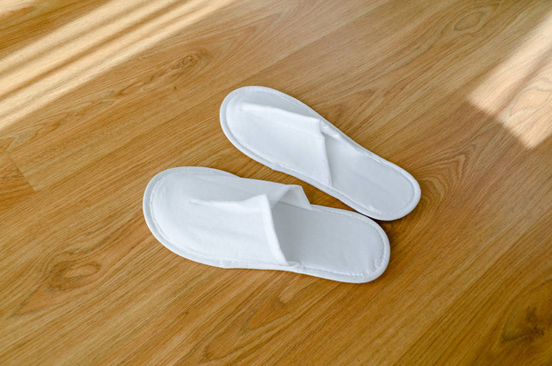 Pár nových jednorázových pantoflí leží na dřevěné podlaze - Fotografie, Obrázek