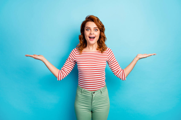 Portrait of astonished funky mature woman hold demonstrate unbelievable adverts recommend suggest select incredible promotion wear white jumper isolated over blue color background - Foto, imagen