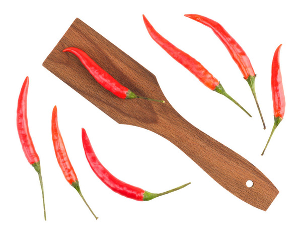 Red chili pods and wooden spatula white isolated background. Indian cuisine, ayurveda, naturopathy concept - Photo, Image