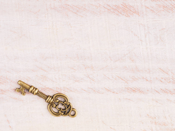 Antique bronze key on light brown wooden background with copy space - Valokuva, kuva