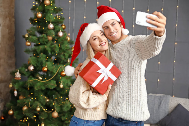 Счастливая пара с рождественским подарком делает селфи дома
 - Фото, изображение