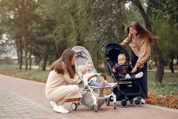 Two young mothers walking in a autumn park with carriages - Fotografie, Obrázek