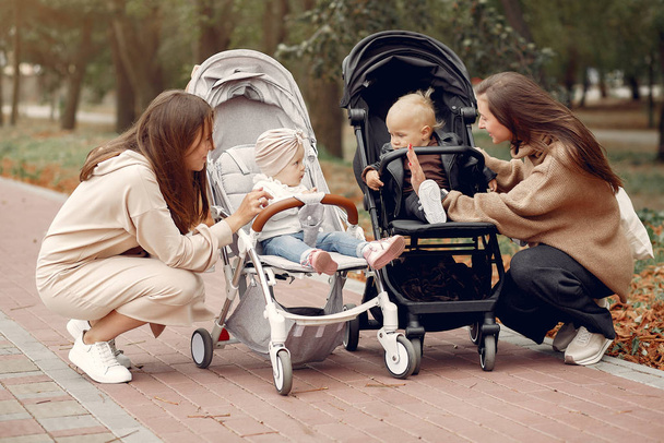 Two young mothers walking in a autumn park with carriages - Foto, Imagem