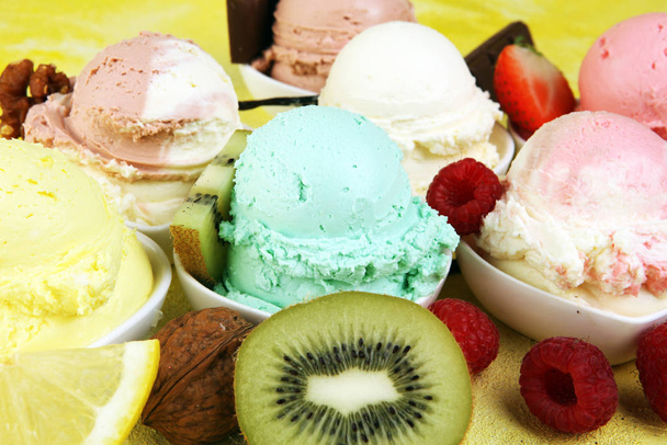 Vários de sabor de sorvete com mirtilo fresco, morango, kiwi, limão, configuração de baunilha em fundo rústico. Gelado de verão e doce
 - Foto, Imagem