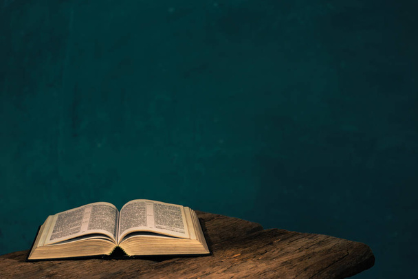Otwórz Biblię na czerwonym drewnianym stole. Piękne zielone tło ściany. - Zdjęcie, obraz