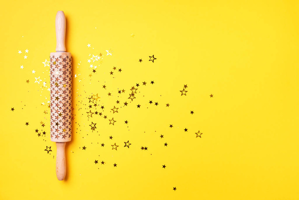 Rolling pin, gold glitter stars on yellow background. Top view. Copy space. Christmas baking concept. Holidays composition. Banner for menu, recipe, ingredients - Foto, Imagen