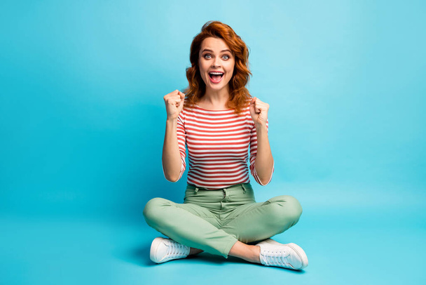 Full length photo of excited woman sit legs crossed celebrate her sporty lottery win raise fists scream yeah wear good look gumshoes isolated over pastel color background - Valokuva, kuva