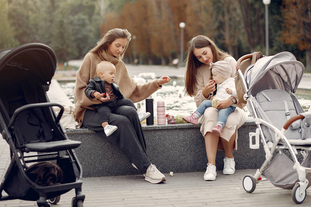 Two young mothers sitting in a autumn park with carriages - Foto, immagini