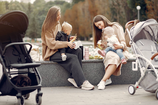 Two young mothers sitting in a autumn park with carriages - Foto, Bild