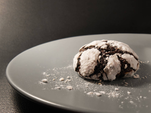 Homemade chocolate cookies. Chocolate brownie cookies in powdered sugar in black background. Selective focus - Photo, Image