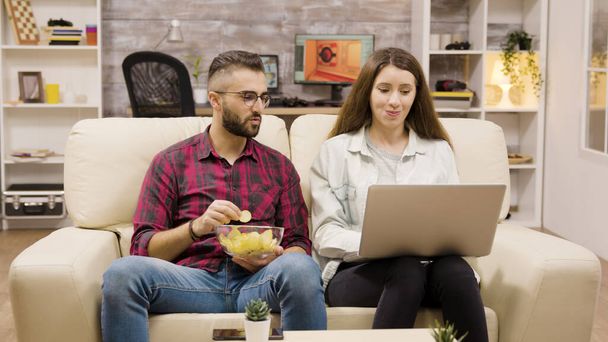Happy young couple sitting on couch doing online shopping - Photo, Image