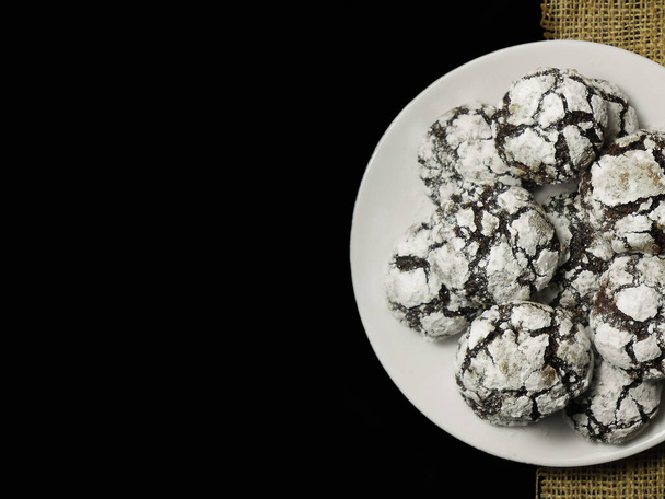 Σπιτικά μπισκότα σοκολάτας. Μπισκότα σοκολάτας σε σκόνη ζάχαρης σε μαύρο φόντο. Επιλεκτική εστίαση. - Φωτογραφία, εικόνα