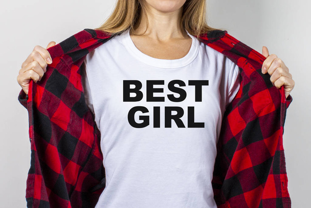 Jonge vrouw in een rood shirt en wit t-shirt op een witte achtergrond. T-shirt sms toegevoegd Beste meisje. Concept vriend, shock, verrassing. Banner. - Foto, afbeelding