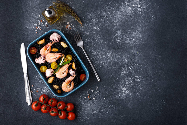 vue de dessus excellent dîner de fruits de mer avec spaghettis noirs à l'encre de seiche, légumes, couverts sur fond gris
 - Photo, image