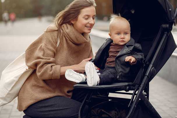 Young mother walking in a autumn park with carriage - Foto, afbeelding