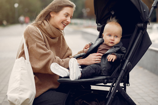 Young mother walking in a autumn park with carriage - Foto, imagen