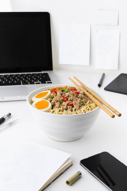 A bowl of instant noodles with egg on white wooden table. What people in asia who have urban lifestyle eat in the end of the month. Food reflecting urban city life. Instant noodle is easy cook in daily life. - Foto, Imagem