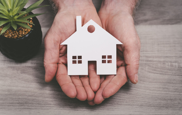 Hände, die ein Haus schützen; Symbol der Hausversicherung - Foto, Bild