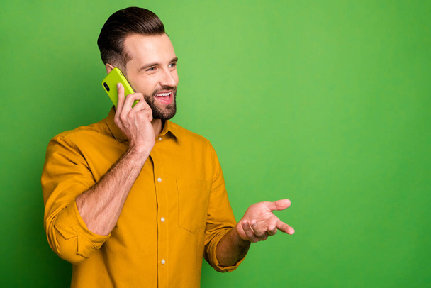 Close-up portrait of his he nice attractive cheerful cheery bearded guy in formal shirt discussing life news on phone isolated on bright vivid shine vibrant green color background - Fotoğraf, Görsel