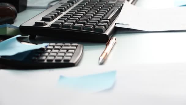 Notities, pen, rekenmachine en een toetsenbord op het bureau. - Video